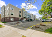 Thumbnail 9 of 26 - A row of apartment buildings with cars parked in front.