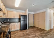 Thumbnail 13 of 26 - A kitchen with wooden cabinets and a black fridge.