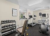 Thumbnail 21 of 28 - A gym with a variety of equipment including a treadmill, a stationary bike, a rowing machine, and a bench press.