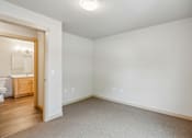 Thumbnail 20 of 26 - A white room with a carpeted floor and a doorway leading to a bathroom.