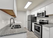 Thumbnail 4 of 18 - a renovated kitchen with stainless steel appliances, granite coutnertops, and white cabinets at Rock Creek
