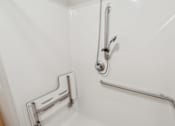 Thumbnail 18 of 26 - A white bathroom with a shower and a grab bar.