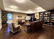 Thumbnail 13 of 19 - A living room with a brown leather couch, a white armchair, and a coffee table.at The Lodge at Johns Road Apartments, Huntsville, AL, 35806
