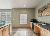 Thumbnail 11 of 26 - A kitchen with wooden cabinets and a black countertop.