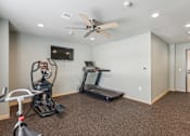 Thumbnail 7 of 26 - A spacious room with a treadmill, exercise bike, and television.