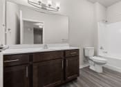 Thumbnail 10 of 24 - a bathroom with a toilet, tub/shower, sink and a mirror in a River Flats Apartment home