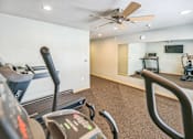 Thumbnail 5 of 26 - A treadmill in a room with a ceiling fan and exercise equipment.