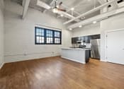 Thumbnail 6 of 25 - a large loft with wood floors, exposed ductwork, and a modern kitchen with stainless steel appliances