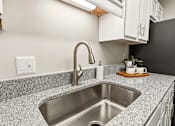 Thumbnail 24 of 41 - A kitchen with a granite countertop and a stainless steel sink.