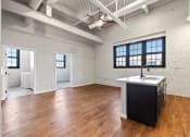 Thumbnail 7 of 25 - an open living room with a kitchen and exposed ductwork at Brooke Street Lofts