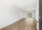 Thumbnail 37 of 37 - A room with white walls and wooden flooring with a door on the right.