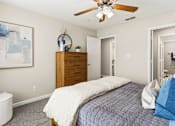 Thumbnail 27 of 41 - A bedroom with a bed, dresser, and a ceiling fan.