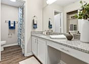 Thumbnail 28 of 41 - A bathroom with a toilet, sink, and a mirror.