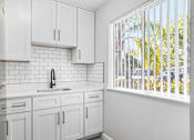 Thumbnail 14 of 37 - A kitchen with white cabinets and a white sink.