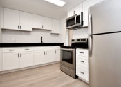 Thumbnail 18 of 36 - a white kitchen with stainless steel appliances and white cabinets