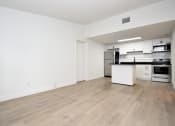 Thumbnail 25 of 36 - an empty living room and kitchen with white walls and wood-style floors