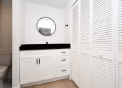 Thumbnail 27 of 29 - a bathroom with white cabinets, black granite countertop, and a mirror