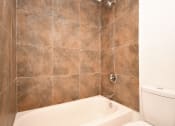 Thumbnail 31 of 36 - a tiled bathroom with a tub and a toilet