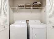 Thumbnail 30 of 41 - A laundry room with two washing machines and a shelf above them.