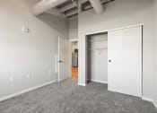 Thumbnail 10 of 25 - a bedroom with a closet and a carpeted floor at Brook Street Lofts