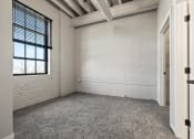 Thumbnail 12 of 25 - a bedroom with carpeting, a large window, and a whitewashed brick wall