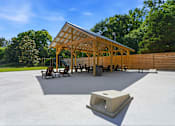Thumbnail 36 of 41 - A pavilion with a roof made of wooden beams is surrounded by a concrete floor and a wooden fence.