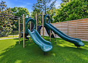 Thumbnail 37 of 41 - A playground with a green slide and a wooden fence.