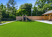 Thumbnail 38 of 41 - A green artificial turf in a backyard with a slide and wooden fence.