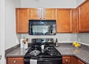 Thumbnail 27 of 56 - Centerville Manor's model kitchen with wood cabinets and black appliances