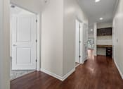 Thumbnail 11 of 28 - A hallway with a white door and brown flooring.