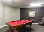 Thumbnail 19 of 26 - A pool table with a red cloth and a clock on the wall.