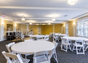 Thumbnail 14 of 26 - A room with tables and chairs is set up for an event.