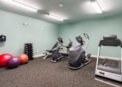 Thumbnail 18 of 26 - A room with a treadmill, exercise bike, and a rowing machine.