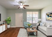 Thumbnail 4 of 26 - A living room with a couch, chair, and potted plant.