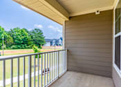 Thumbnail 9 of 26 - A balcony with a metal railing and a view of a green lawn and trees.