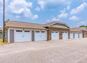 Thumbnail 25 of 26 - A building with a brown roof and white garage doors.