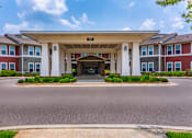 Thumbnail 2 of 26 - A building with a covered walkway entrance and a sign above it.