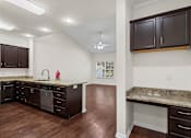 Thumbnail 9 of 28 - A kitchen with dark brown cabinets and a granite countertop.