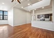 Thumbnail 3 of 25 - a spacious living room and kitchen with wood floors, ceiling fans, and natural light