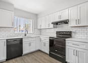 Thumbnail 1 of 37 - A kitchen with white cabinets and black appliances.