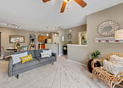Thumbnail 25 of 56 - large Fenwyck Manor apartment home living room, dining room, and kitchen with plush carpeting and ceiling fan