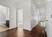 Thumbnail 10 of 28 - A long hallway with white walls and wood floors.