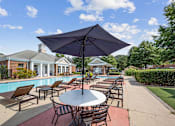 Thumbnail 48 of 56 - a bank of lounge chairs and tables with umbrellas by the pool at Centerville Manor Apartments