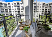 Thumbnail 28 of 40 - A balcony with two chairs and a table with a potted plant on it.