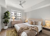 Thumbnail 21 of 40 - A bedroom with a large bed, a ceiling fan, and a potted plant.
