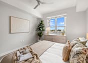 Thumbnail 22 of 40 - A bedroom with a large bed, a ceiling fan, and a window with a view of the city.