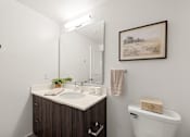 Thumbnail 24 of 40 - A bathroom with a brown vanity and a white toilet.