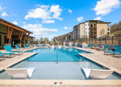 Thumbnail 15 of 43 - a swimming pool with blue chairs and a building in the background