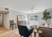 Thumbnail 2 of 14 - a furnished living room with warm wood floors, large windows, an illuminated ceiling fan at Mountainside Apartments