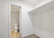 Thumbnail 11 of 14 - a large walk-in closet with a hanging bar and built-in shelving and bathroom access in a Mountainside Apartment